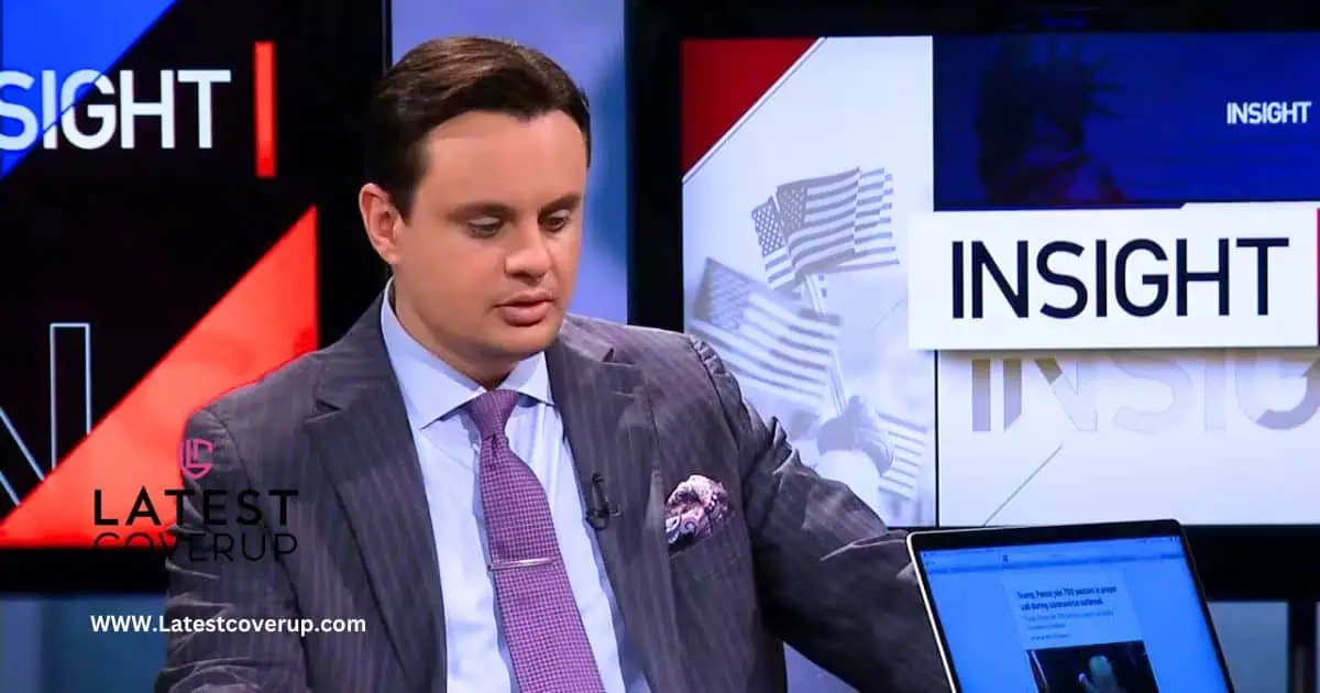 John Rosenstern, a man in a suit and tie, sits in front of a television, engaged in a thoughtful moment